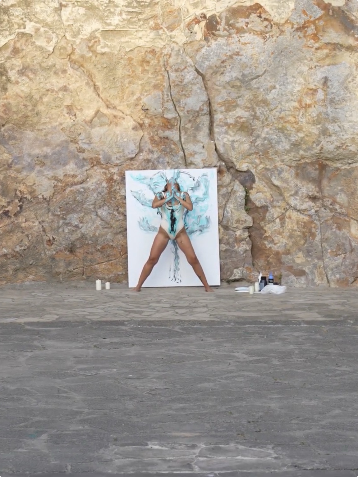 Nina frente a su lienzo, con las manos unidas y el cuerpo cubierto de pintura